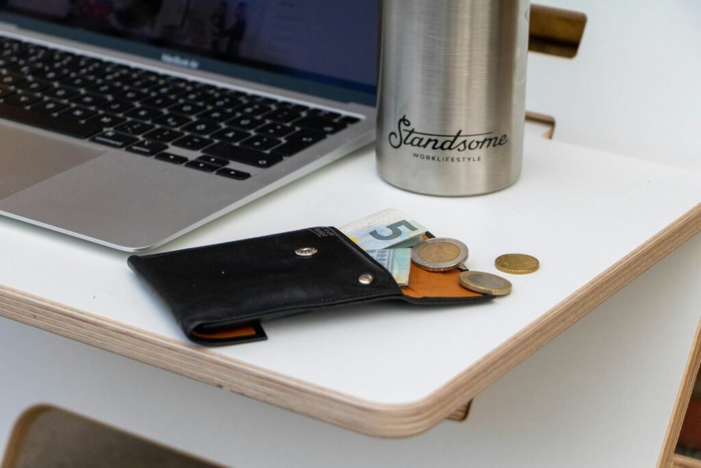 Portefeuille et pièces à côté d’un ordinateur portable